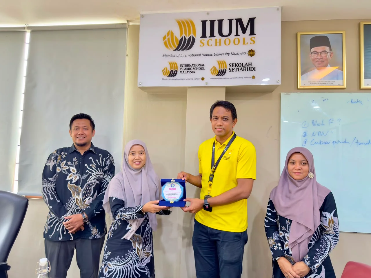 Penyerahan cendera mata di depan papan IIUM Schools dan International Islamic School Malaysia.