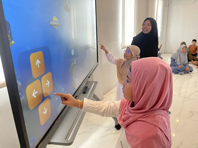 Anak dan pendamping berinteraksi dengan layar pembelajaran.